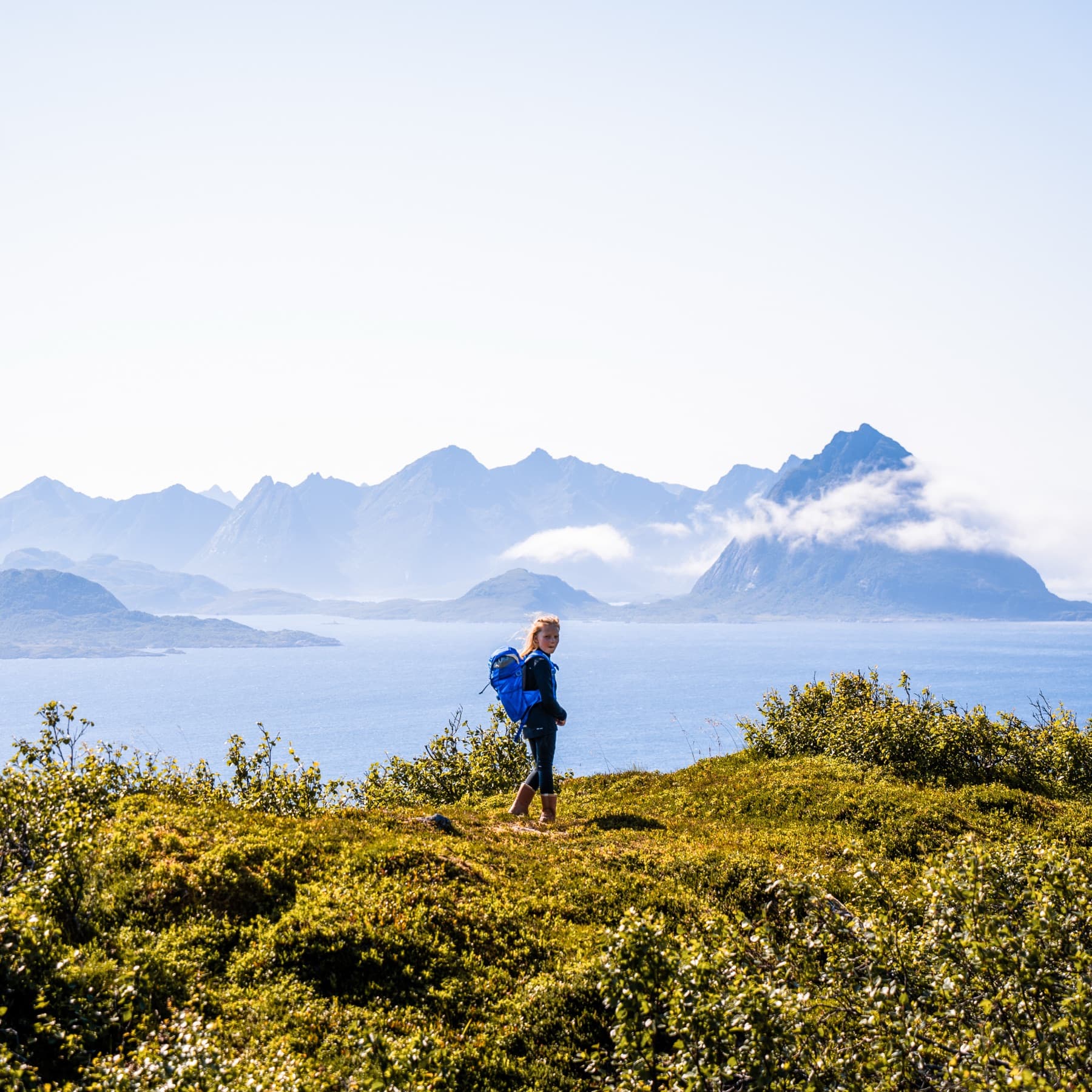 Fotturist alene på fjellplatå med utsikt mot fjord