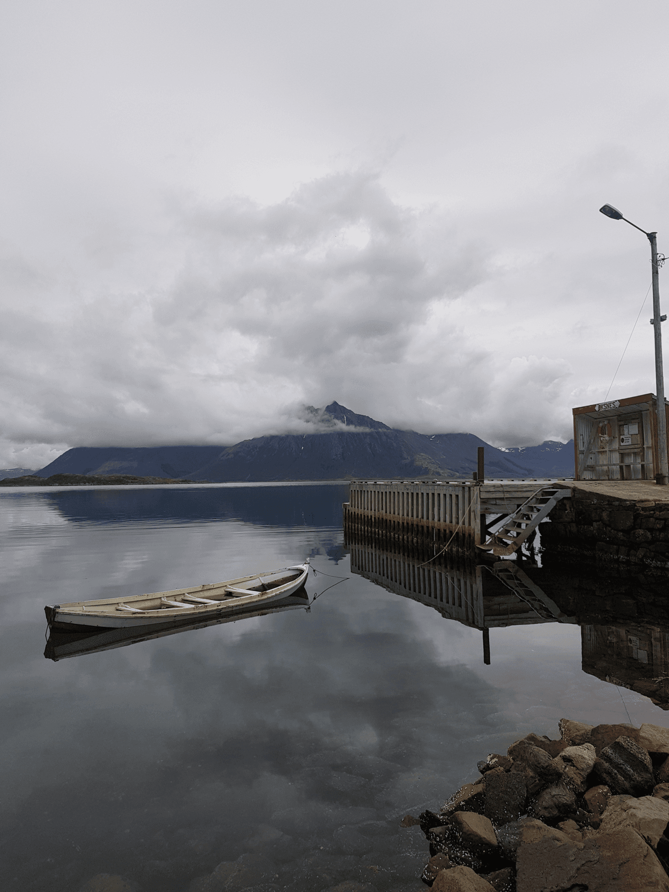Robåt på speilblank fjord ved kaia