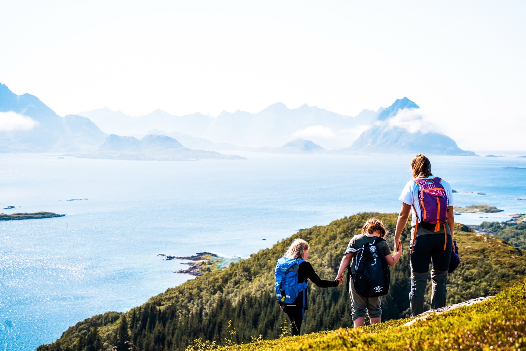 Familie på fjelltur med utsikt mot øyene
