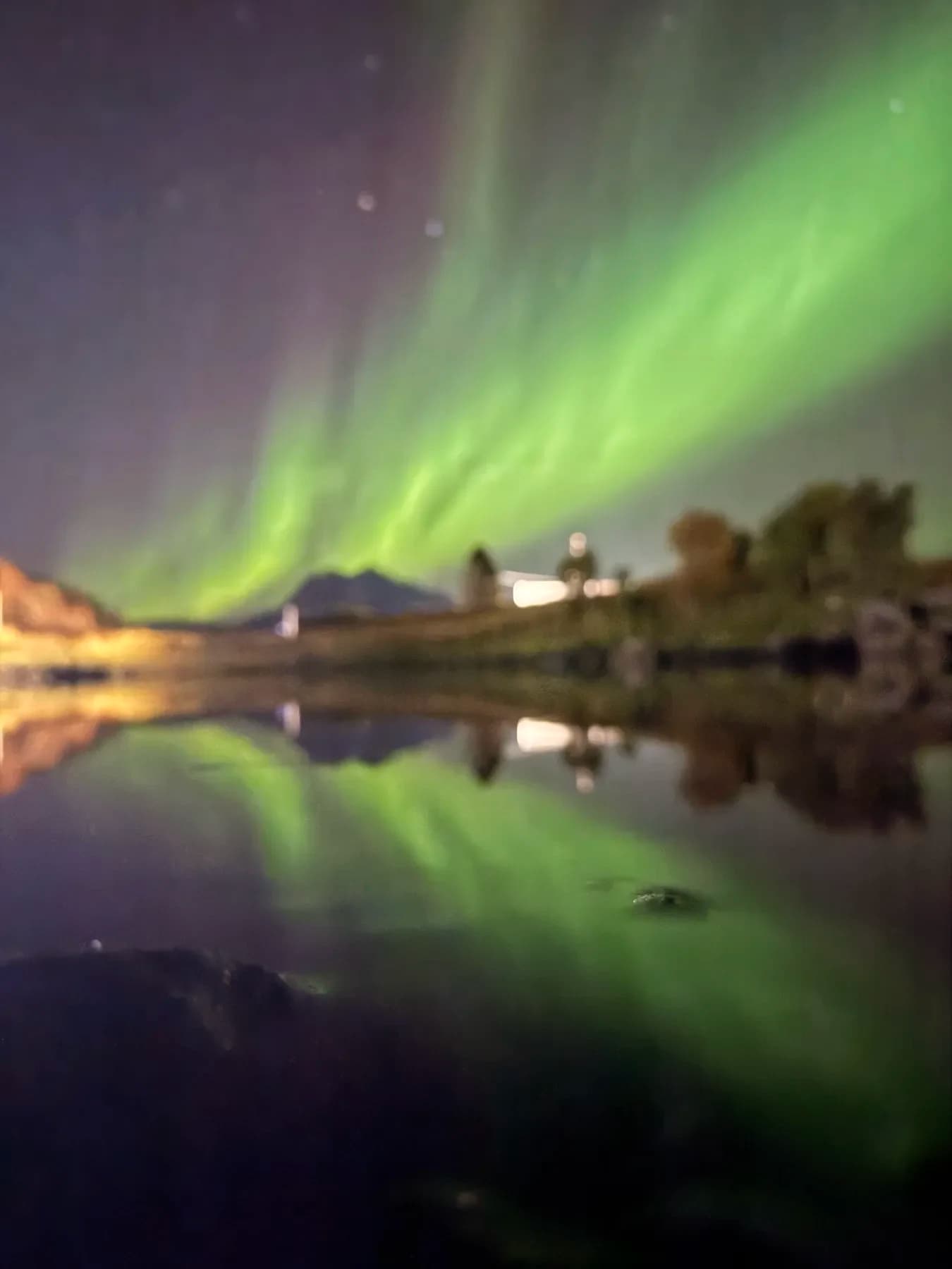 Nordlys og fjell speilet i vannflaten
