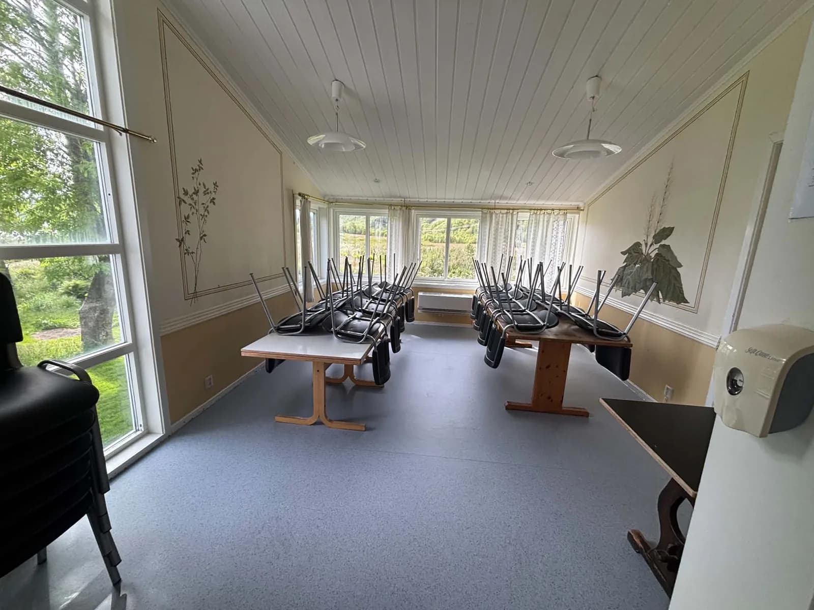 Lyst spisesal med langbord og store vinduer